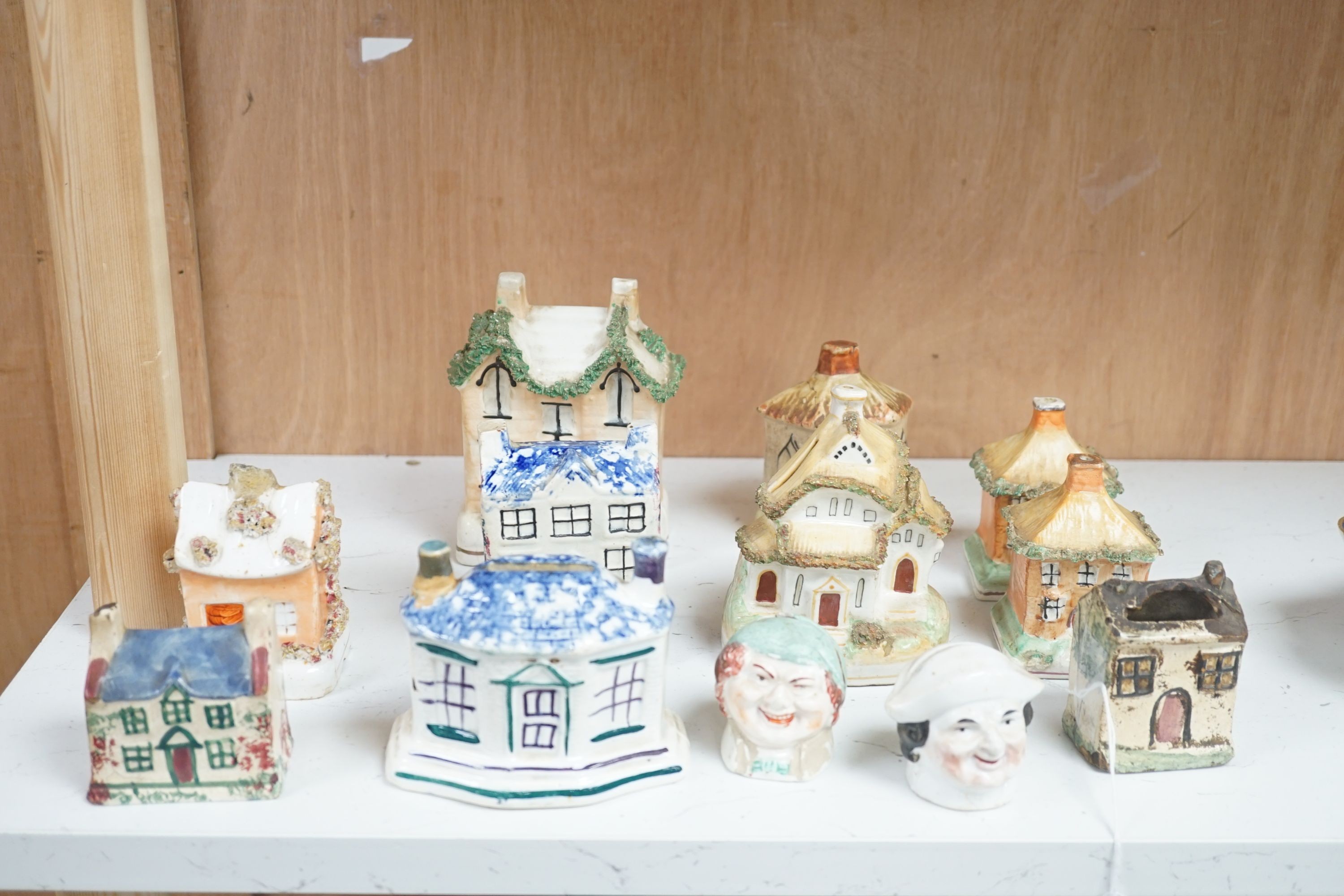 Twelve Staffordshire pottery money boxes, three with sponged decoration, modelled as cottages or heads, tallest 13.5 cms high.